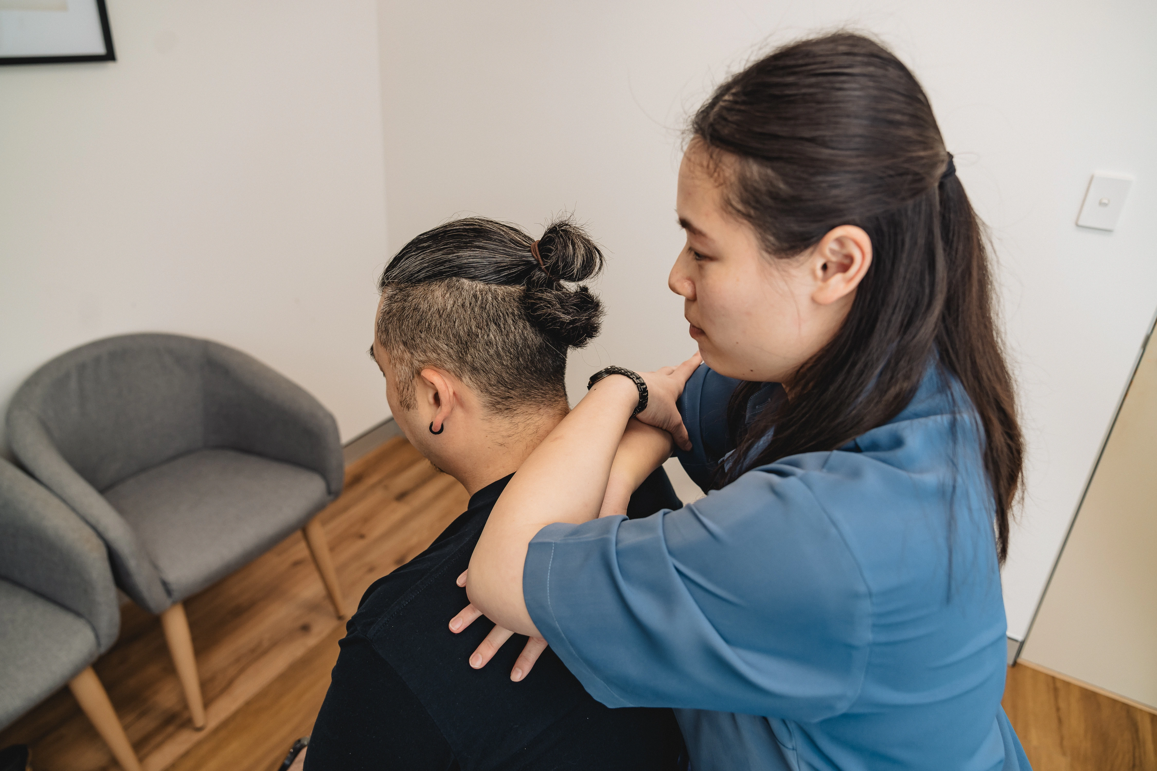 Chiropractor Gianna Lau assessing a patient's neck and shoulders