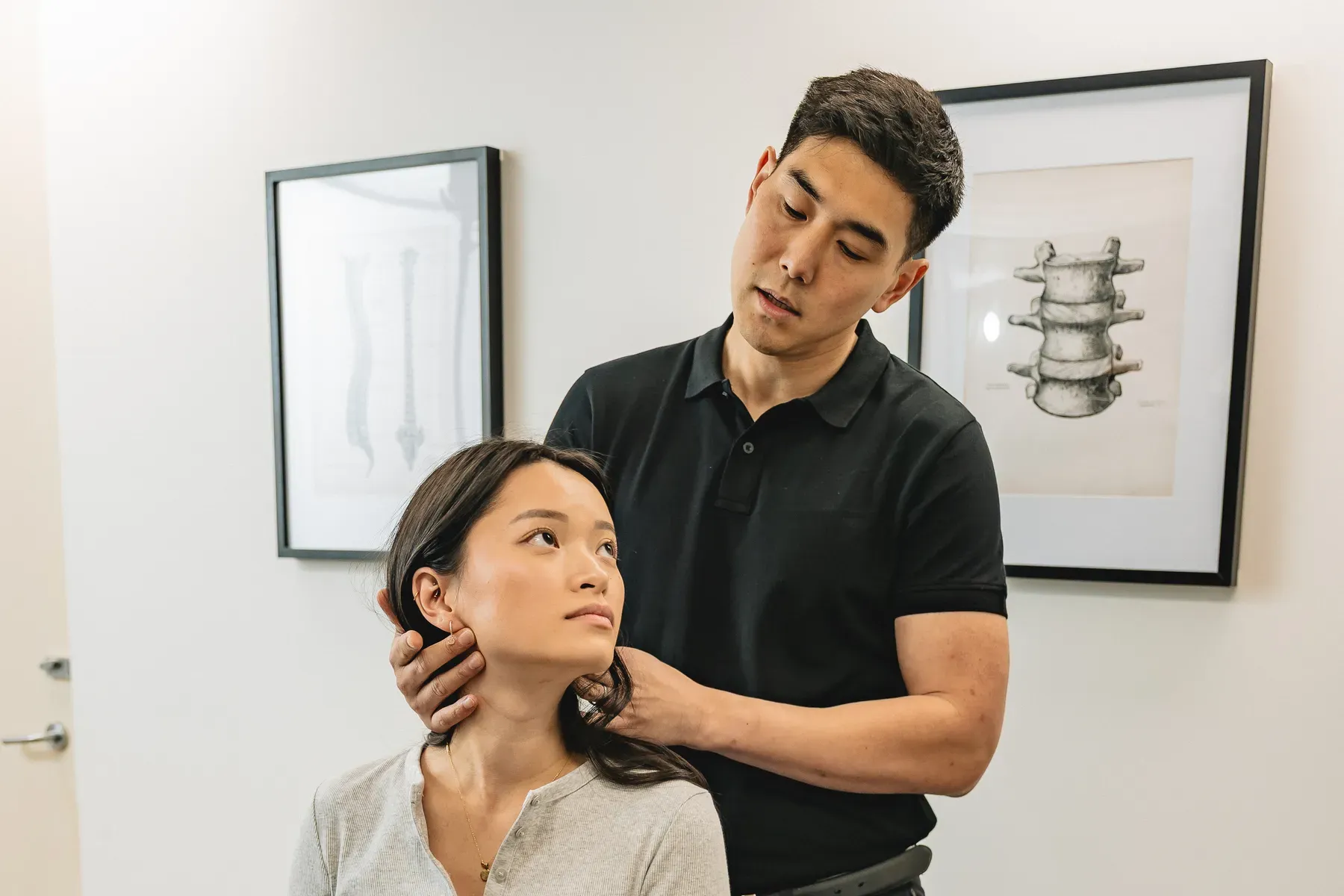 Chiropractor assessing a seated patient's neck movement during a headache and migraine consultation in Chatswood