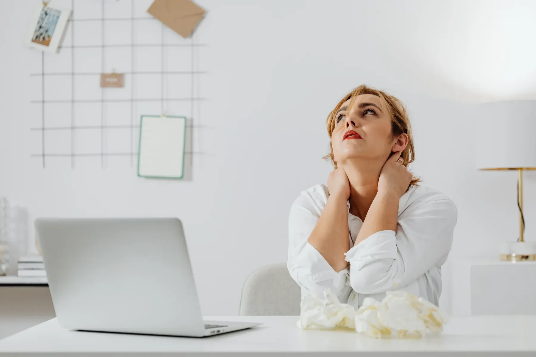 Office worker holding her neck in discomfort due to sustained forward head posture and cervical muscle tension