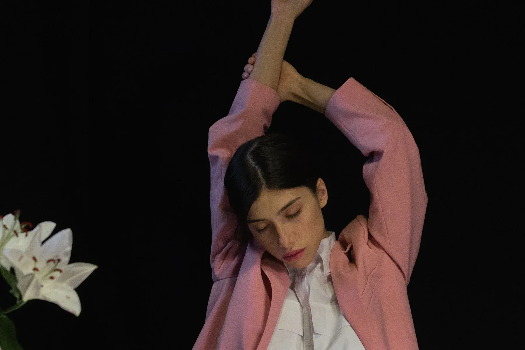 Office professional performing an overhead desk stretch break to relieve shoulder tension and thoracic stiffness during long sitting hours