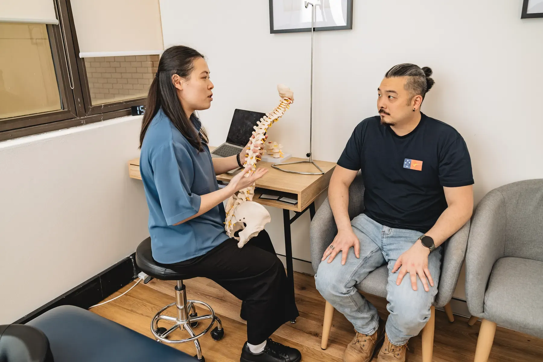 Practitioner explaining a spine model to an adult patient during a consultation at Body Therapy Chiropractic in Chatswood