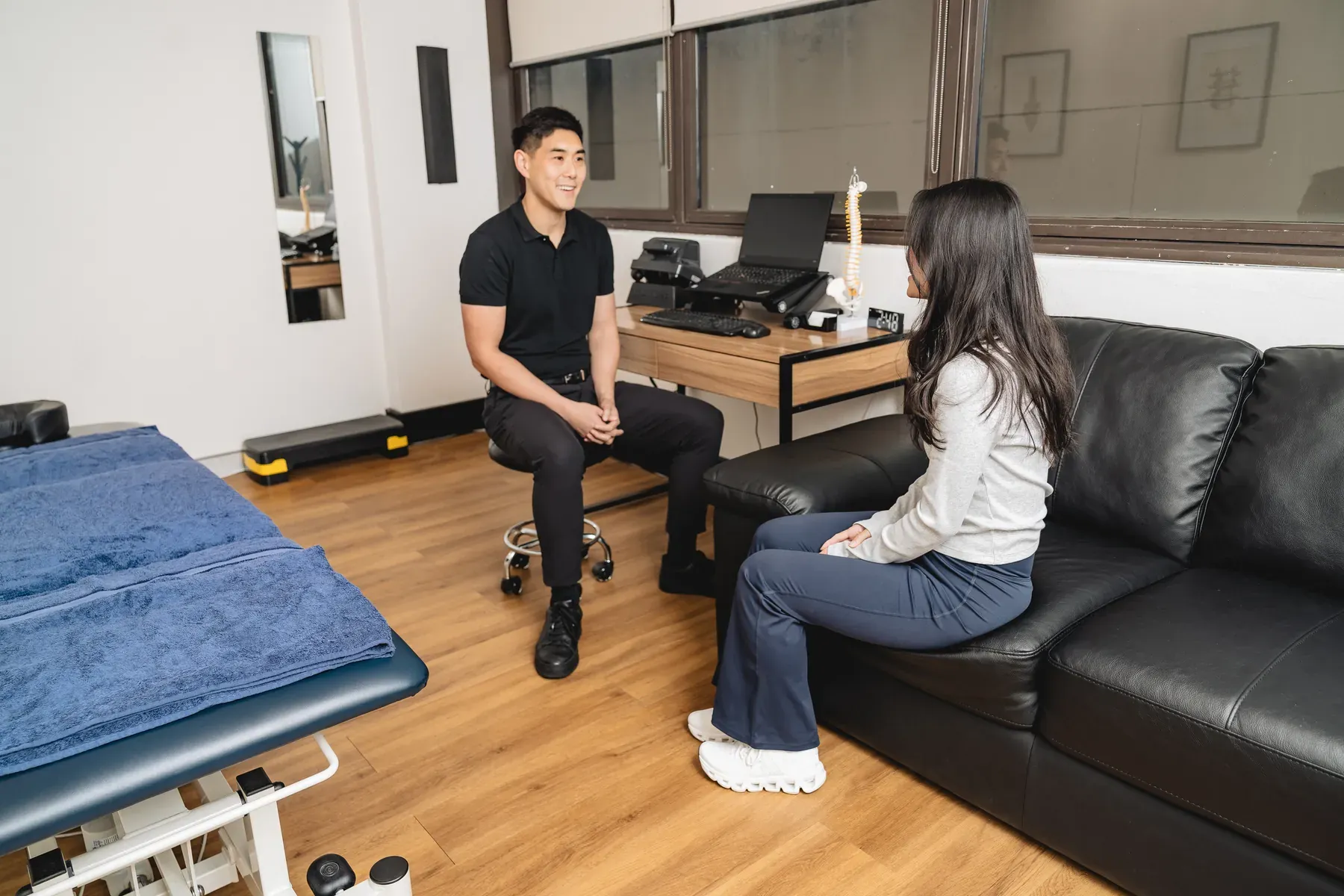 James Zheng speaking with a seated adult during a consultation at Body Therapy Chiropractic in Chatswood