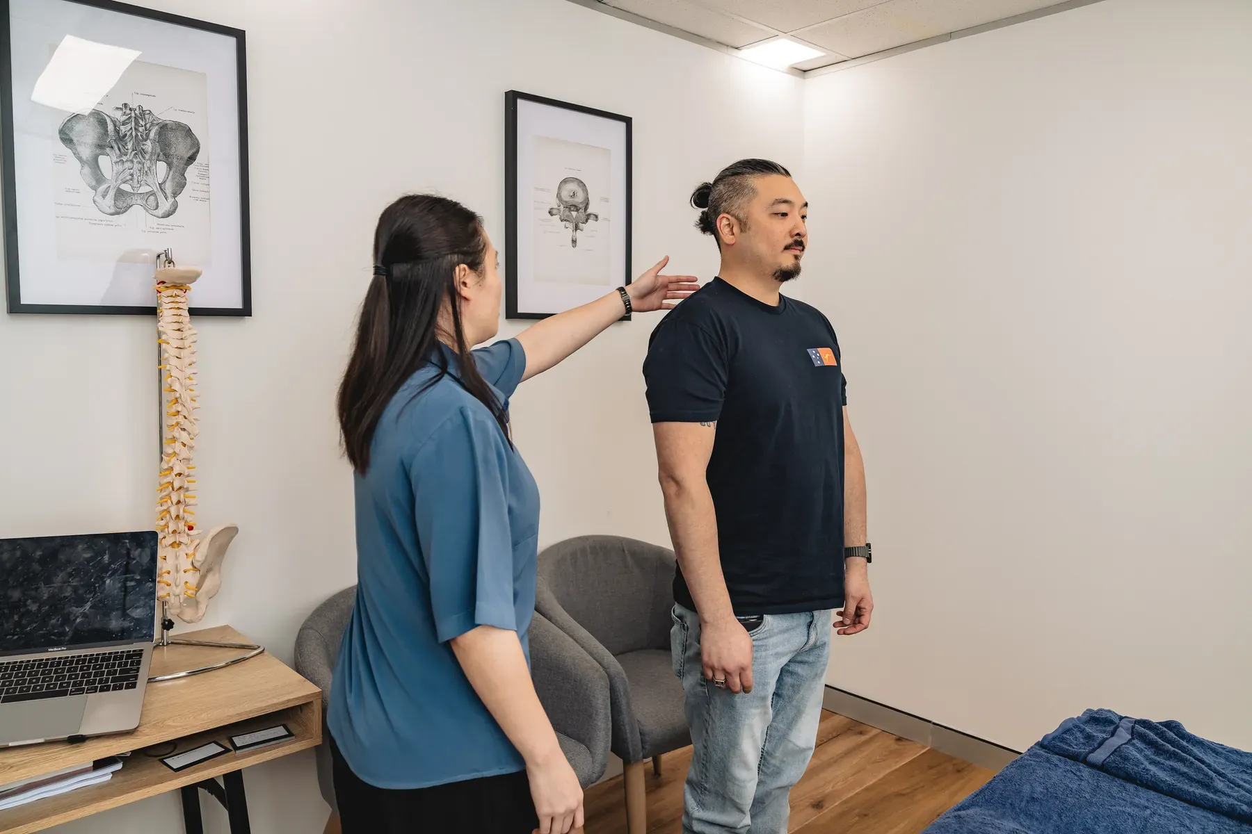 Practitioner assessing a standing adult's shoulder area at Body Therapy Chiropractic in Chatswood