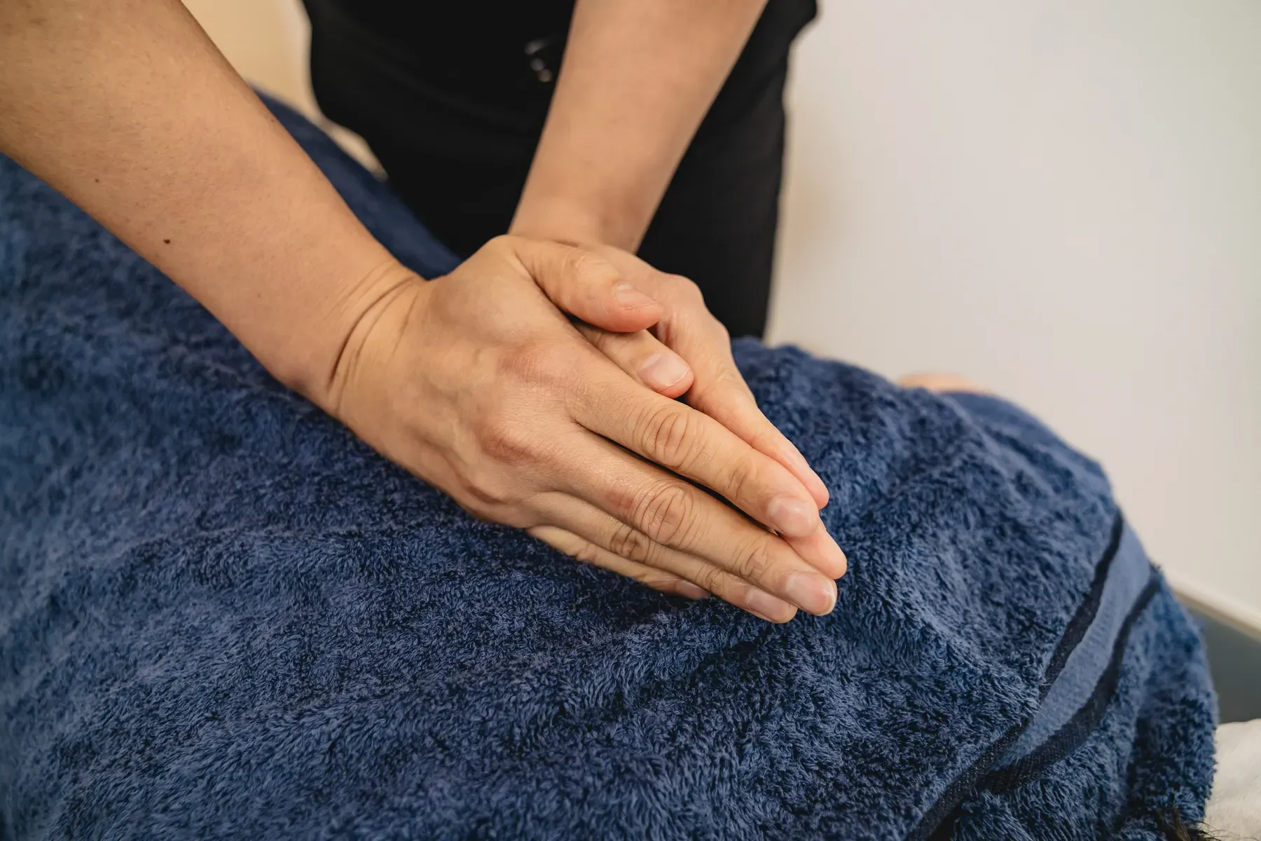 Practitioner applying hands-on soft-tissue therapy to a patient's upper back and shoulder at a Chatswood chiropractic clinic