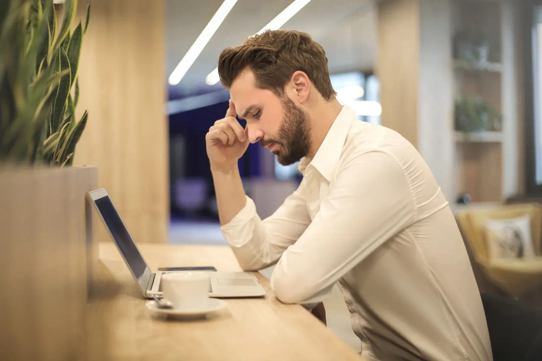 Chatswood office worker slouched over laptop at desk experiencing spinal fatigue and neck strain from prolonged sitting